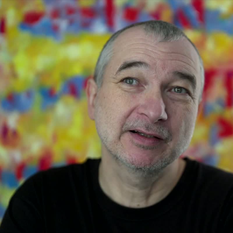 Portrait of Tobias Post, smiling, against a colourful background